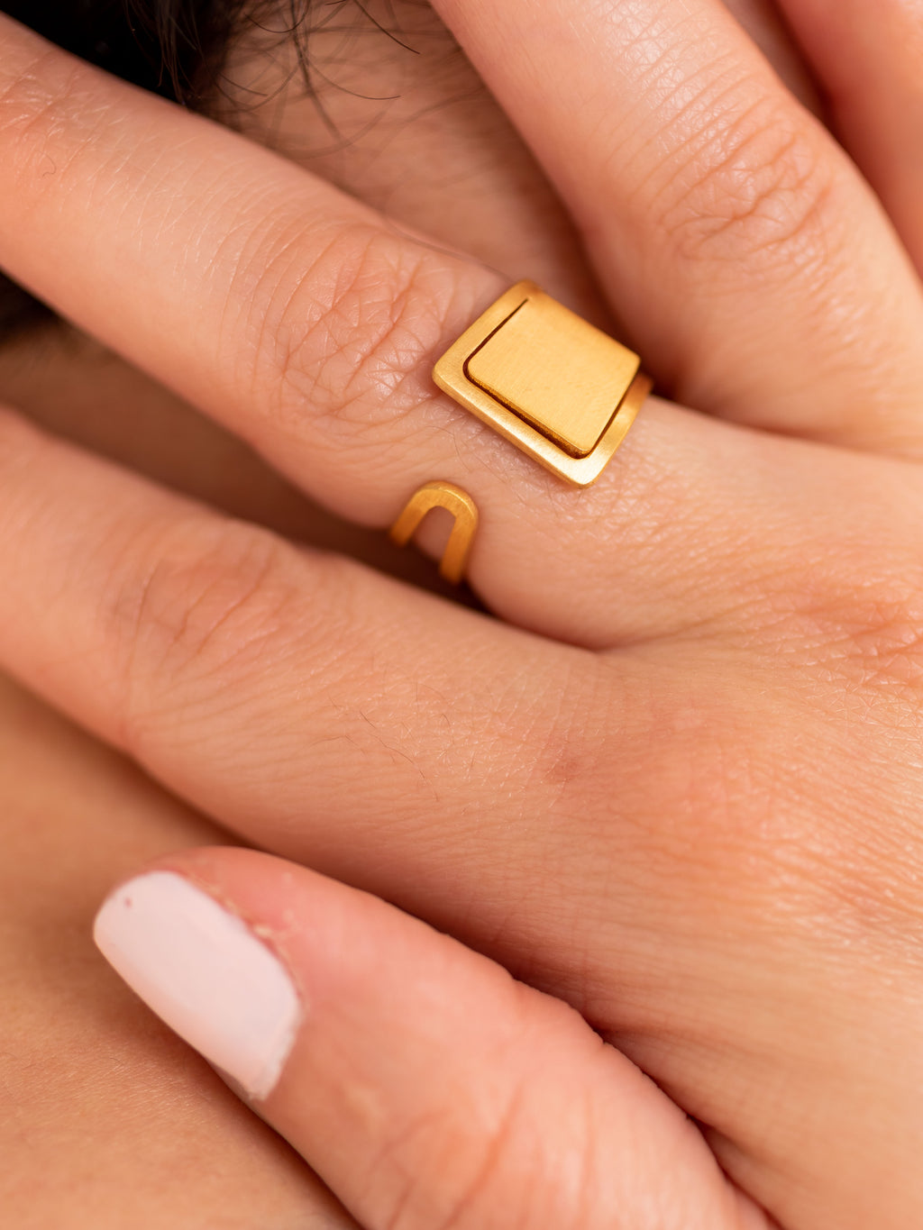 Bague Porta en laiton doré portée.