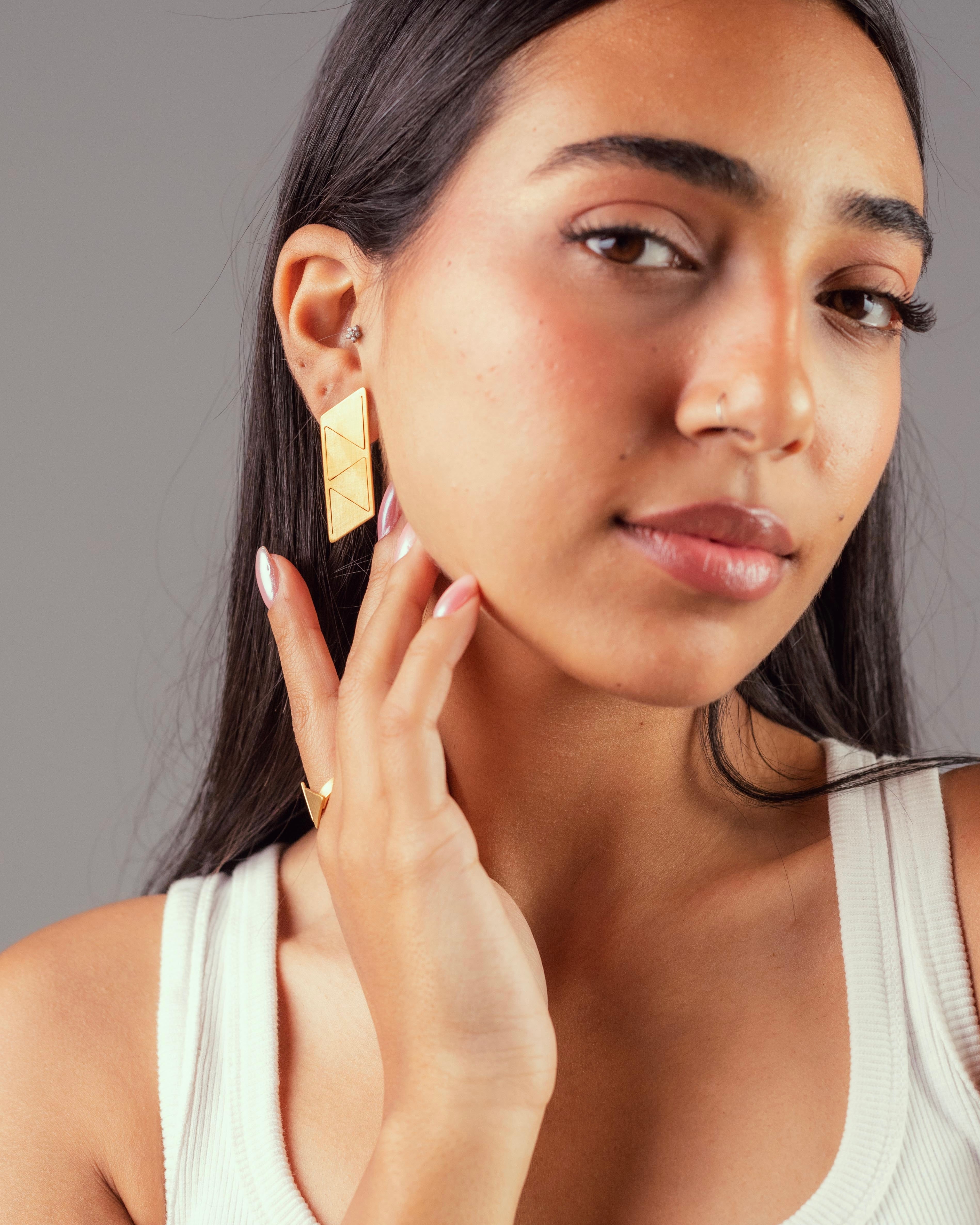 Un mannequin qui porte les boucles d'oreilles 4 triangles Niléa en laiton doré à l'or fin. 