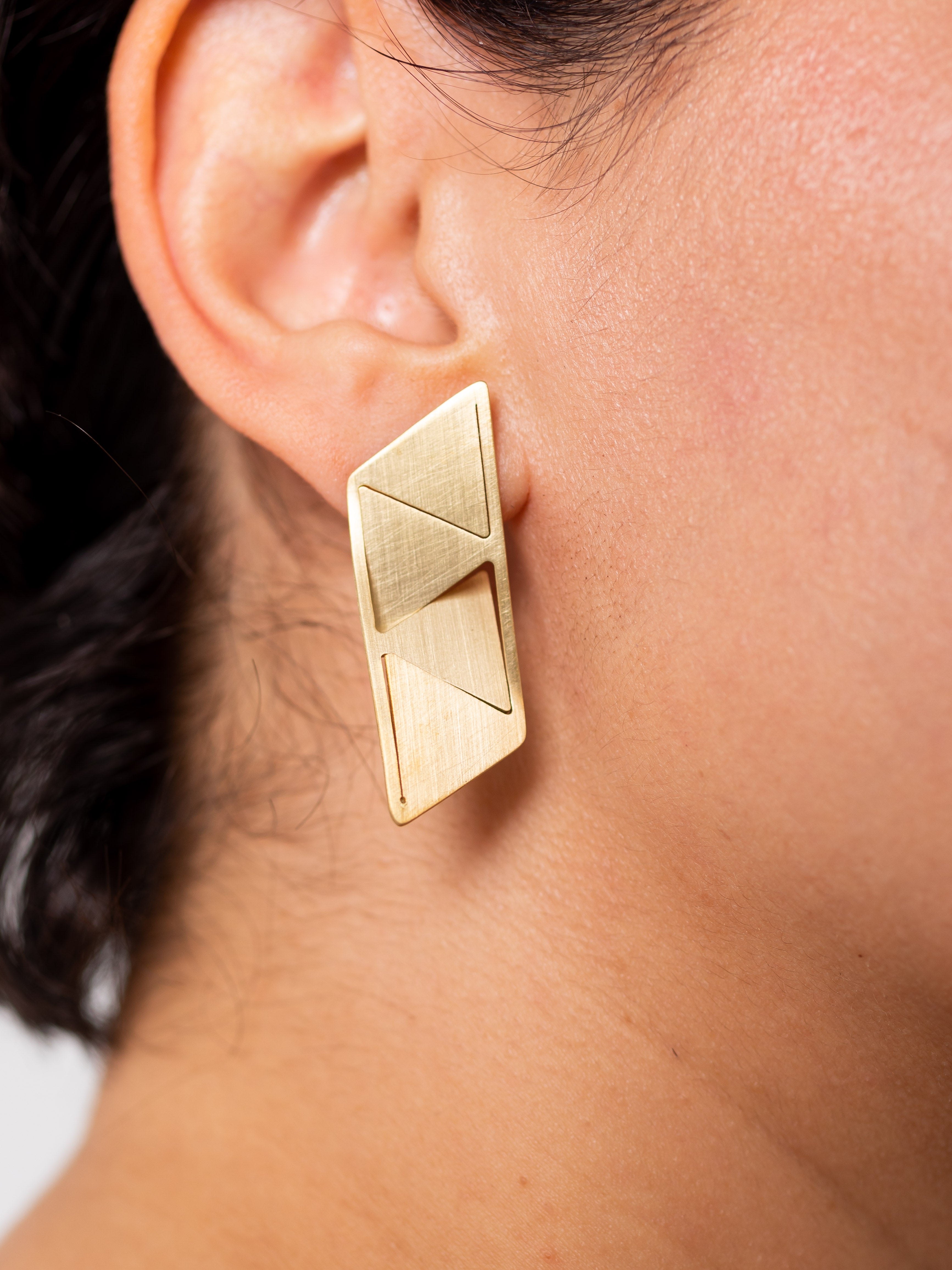 Boucles d’oreilles Triangulate à 4 triangles portées  en laiton brut – bijou graphique et modulable.