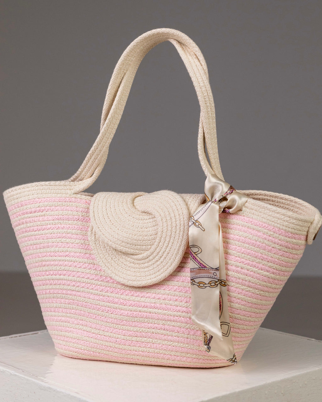 Sac cabas Héliopolis blanc et rose de Maison Niléa, tressé à la main, présenté de face avec son grand rabat en spirale et son foulard satiné amovible noué à l'anse.