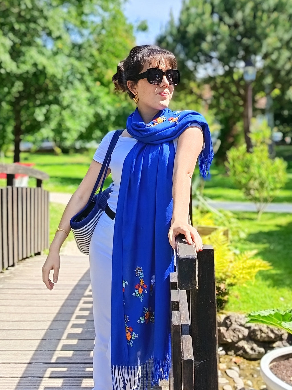 Une femme dans un parc qui porte l’écharpe Samar bleue brodée main Niléa 