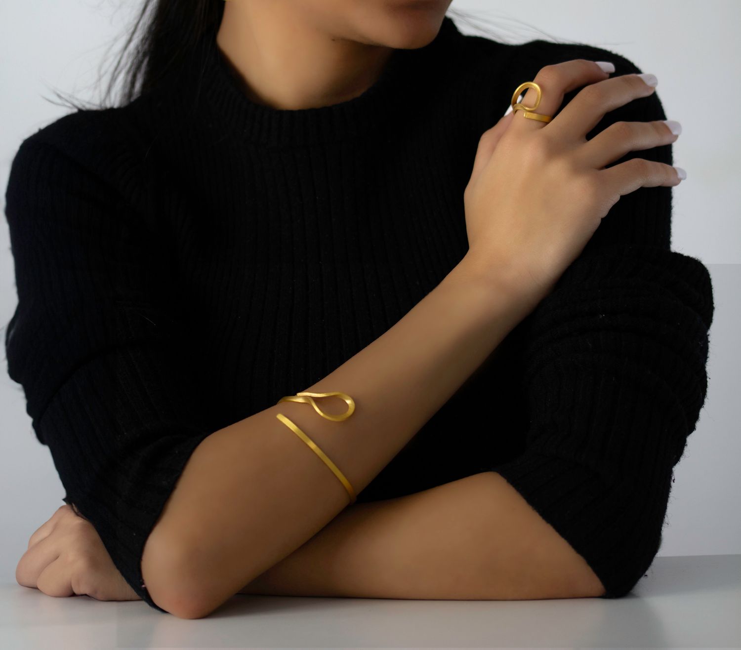 Bague Curl Niléa portée à la main, bijou minimaliste en laiton doré à l'or fin au design fluide.