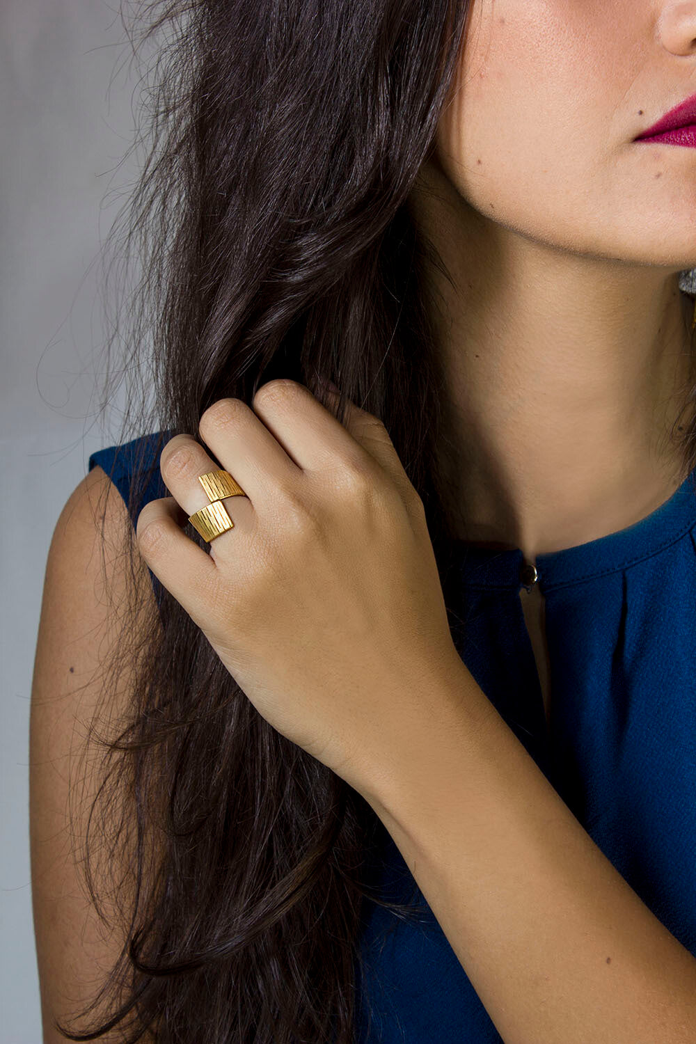 Bague Liquify portée à la main – bague en laiton doré à l'or fin au style minimaliste et fluide.