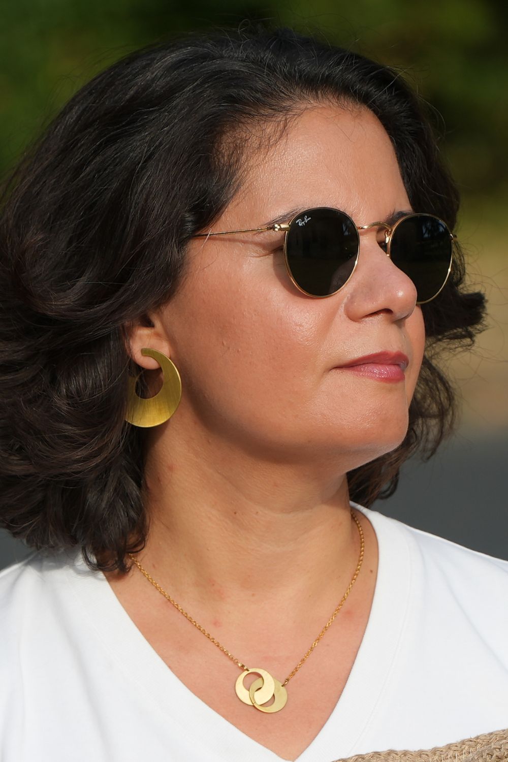 Une femme qui portent les boucles d'oreille courbes larges et le collier duo cercles niléa.