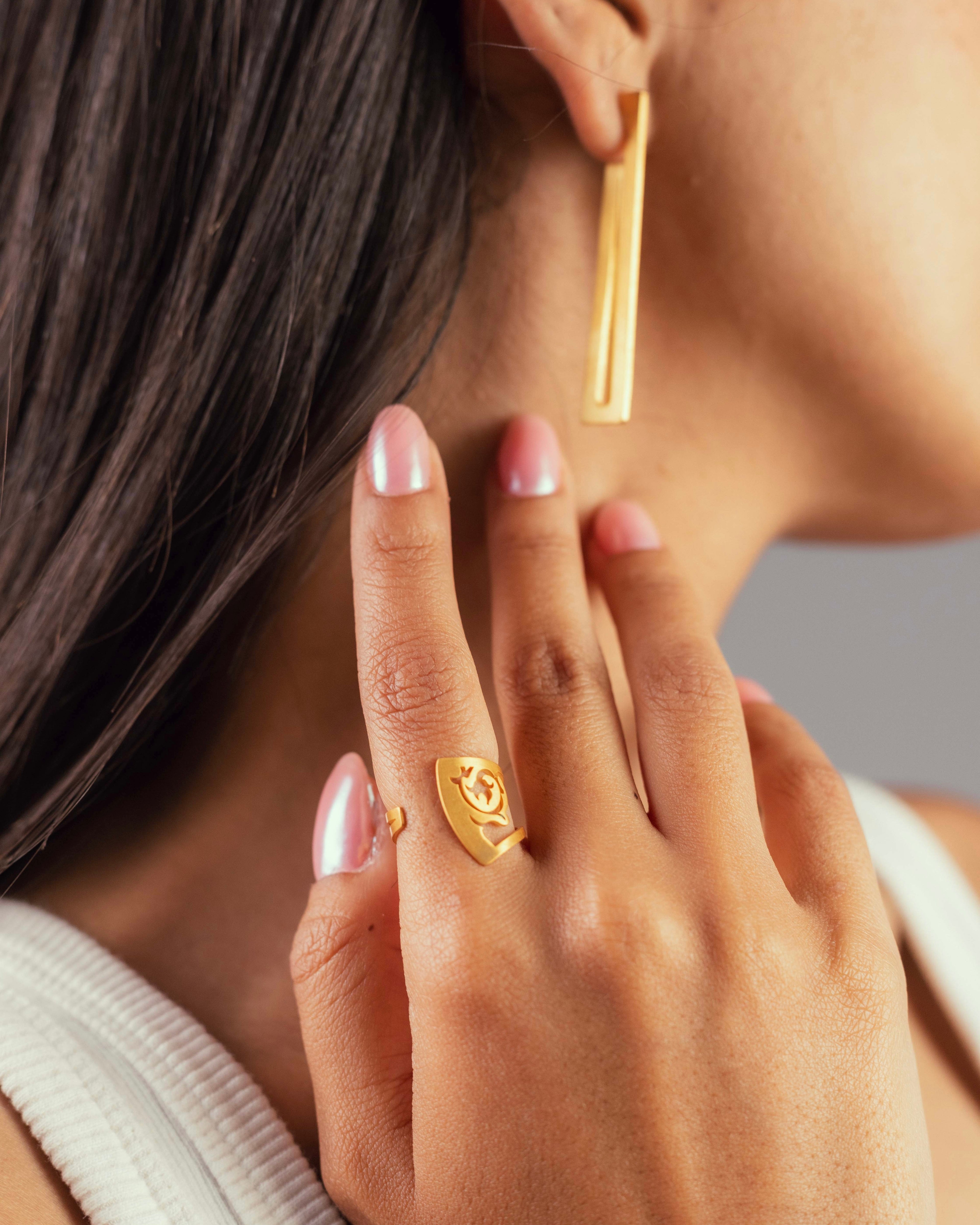 Boucles d'oreilles double Ligne et bague fleur, bijoux en laiton doré Niléa portés.