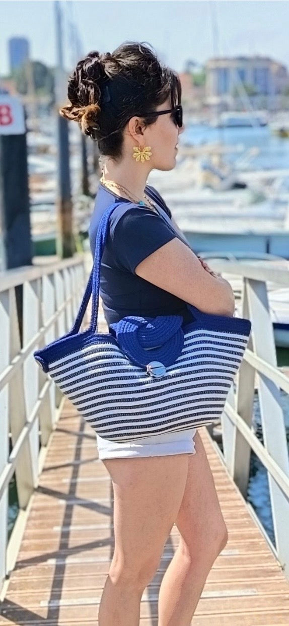 Une femme sur un pont en ambiance estivale, elle regarde l'horizon et porte le sac à main Alexandrie de Maison Niléa 