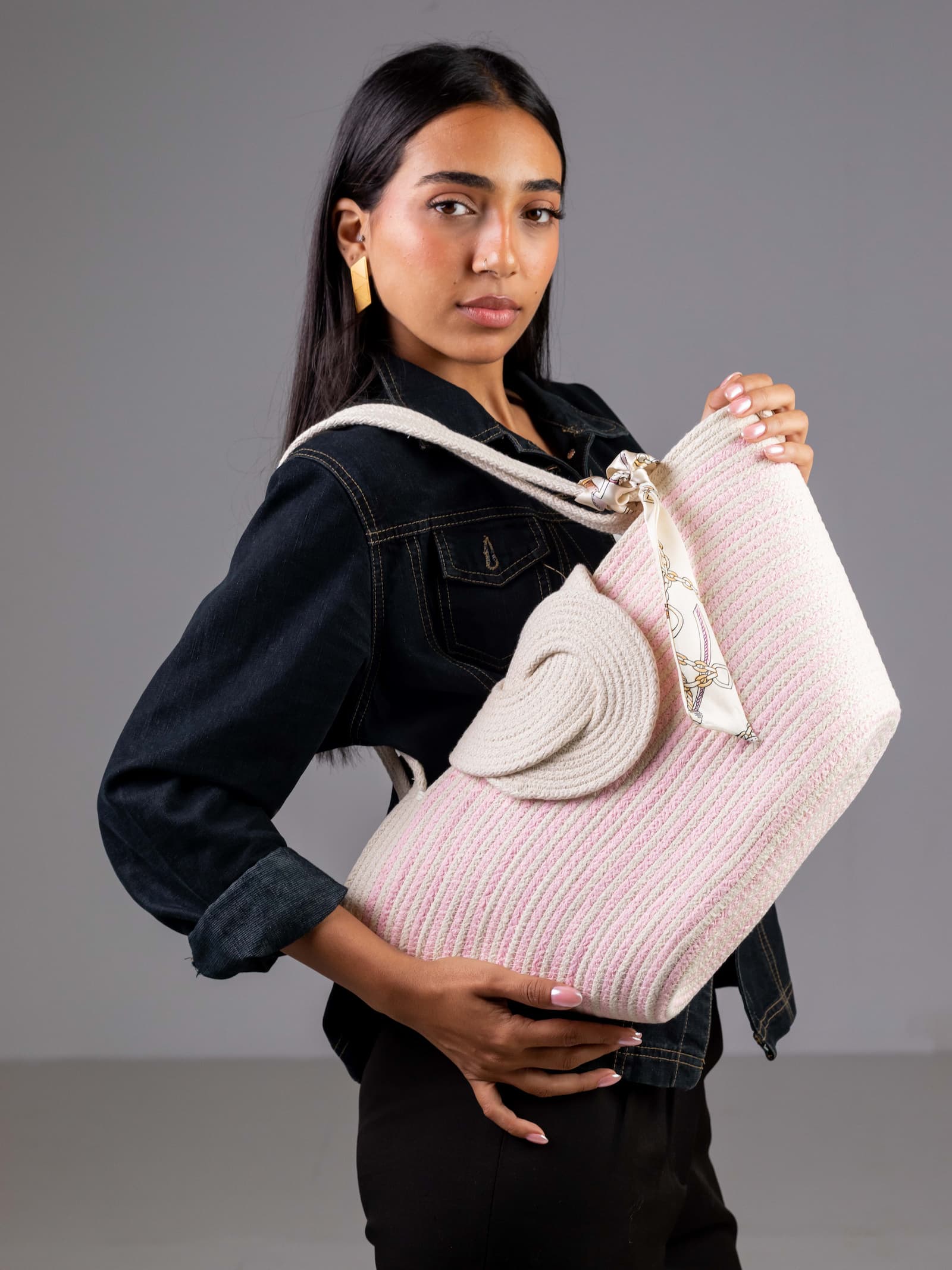 Mannequin portant le sac cabas Héliopolis de Maison Niléa, mettant en valeur son design bicolore blanc et rose, ses anses en corde tressée et son foulard en satin noué à l'anse.