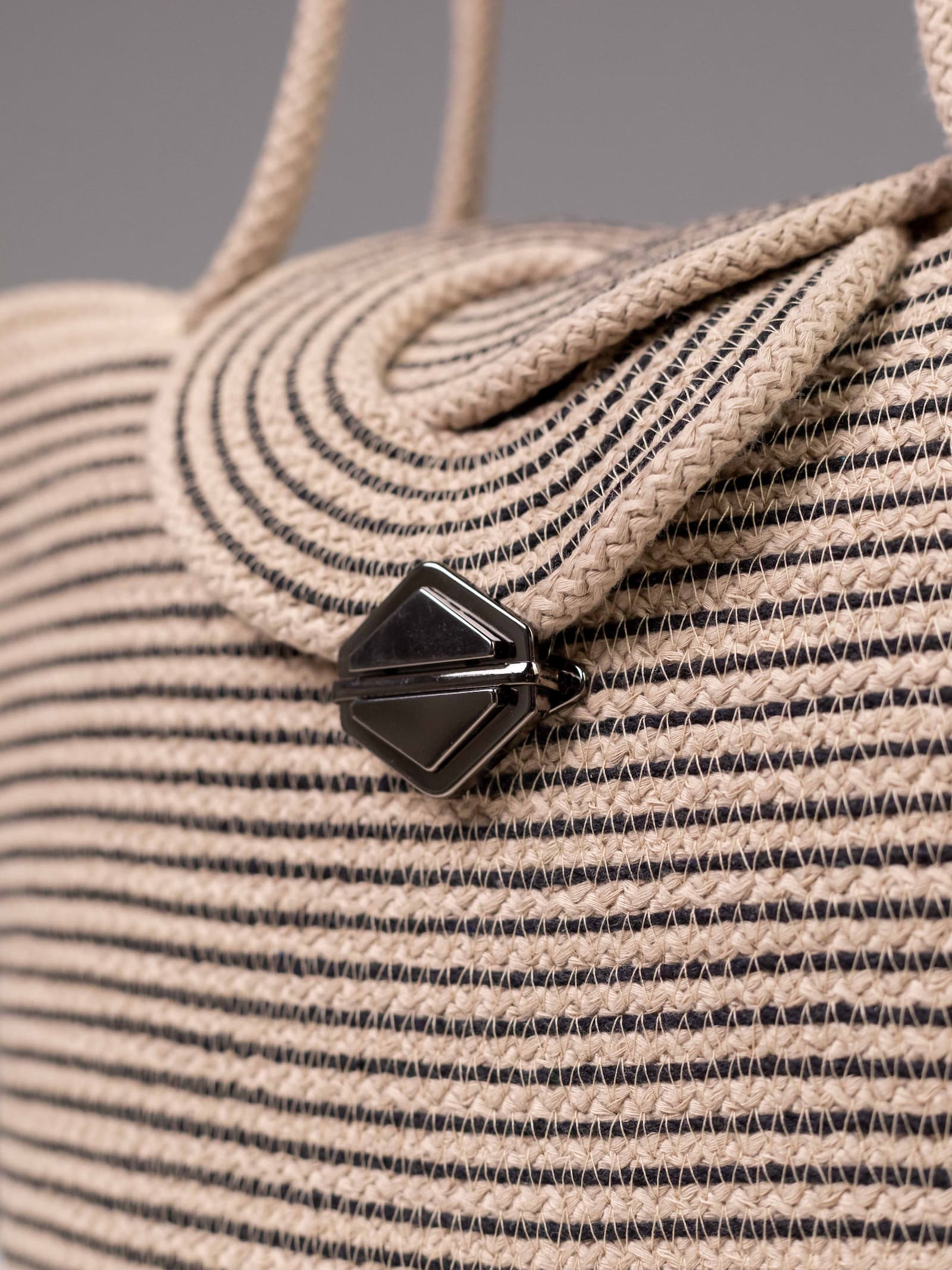 Gros plan sur les détails des finitions du sac Sahara, montrant le tressage artisanal minutieux et le fermoir métallique noir laqué.