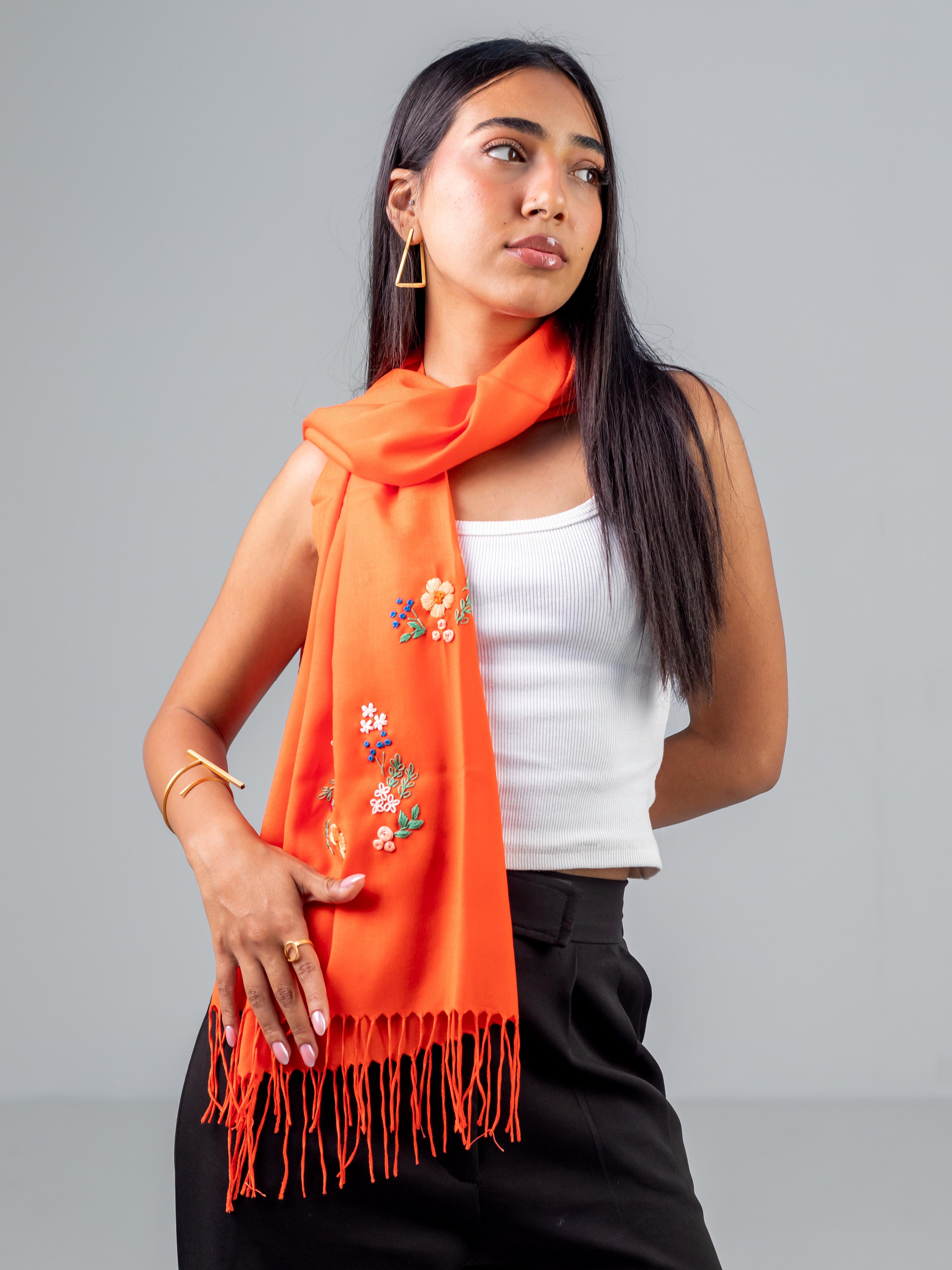 Un mannequin qui porte l'écharpe Nour orange Niléa montrant la broderie sur un côté