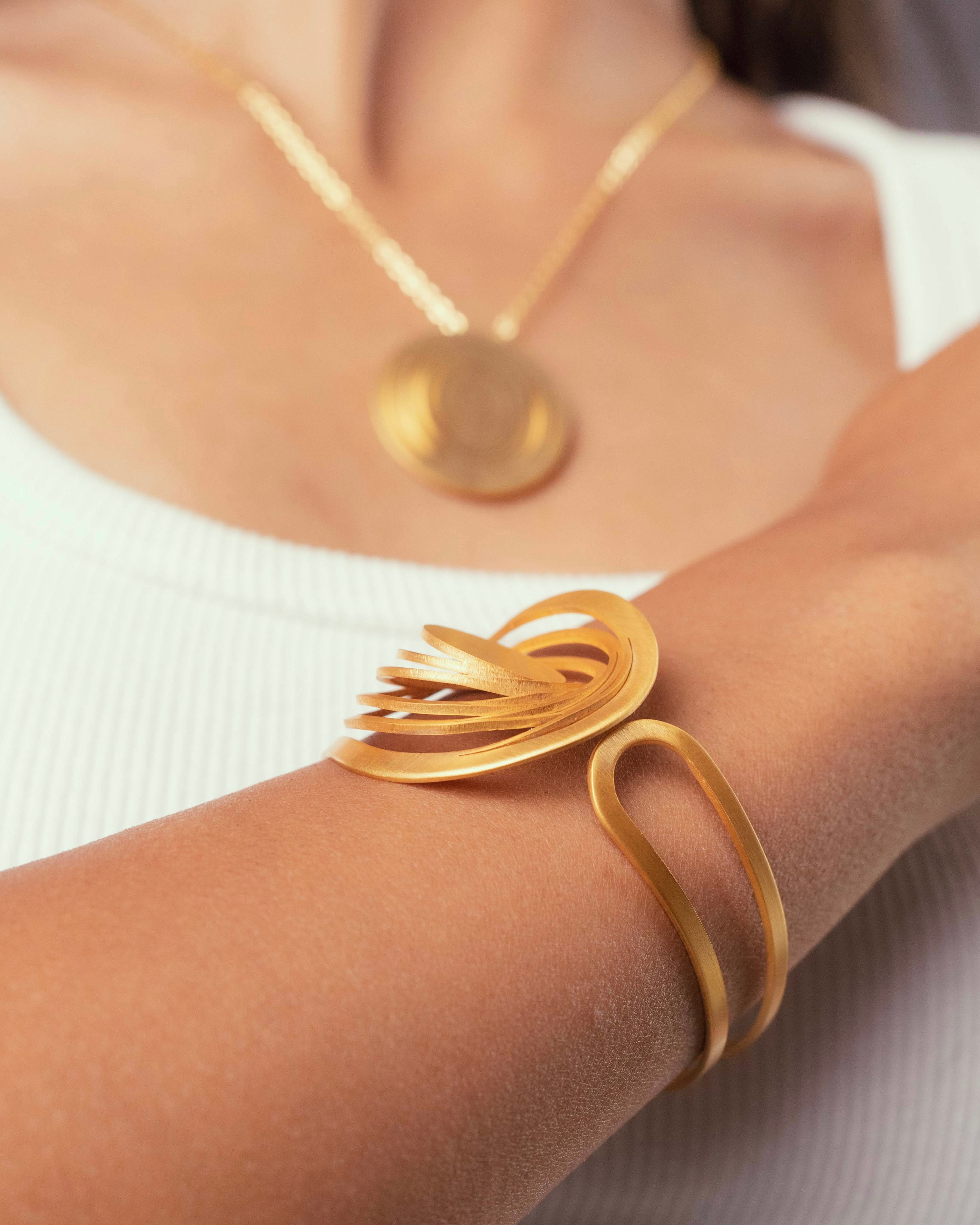 Bracelet manchette Liquify Orbits doré à l’or fin porté au poignet, bijou artisanal modulable Maison Niléa en laiton doré.