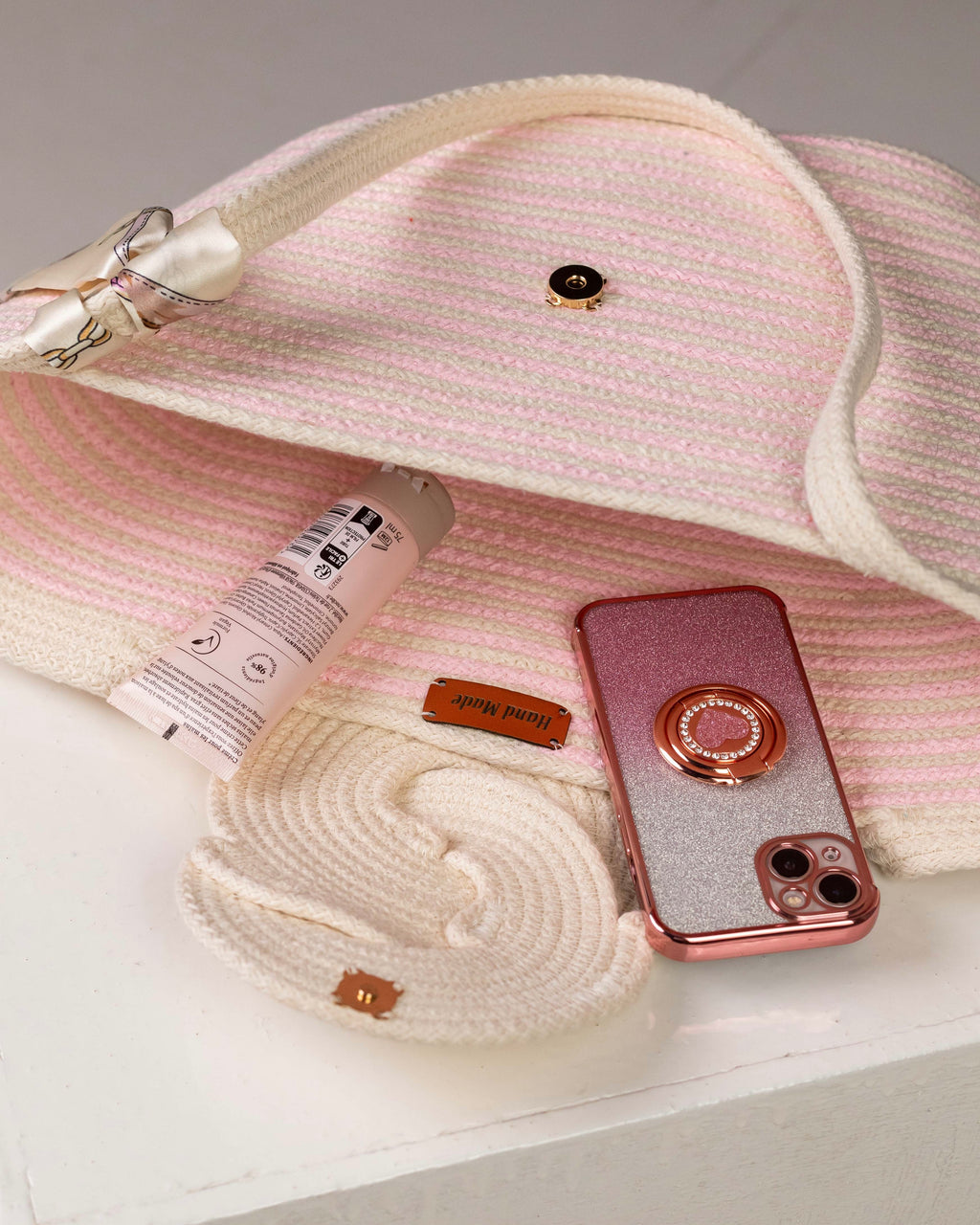 Vue plongeante sur l'intérieur ouvert du sac Héliopolis, montrant sa capacité avec un téléphone portable, une crème pour les mains et son bouton de fermeture aimanté sur le rabat en relief.