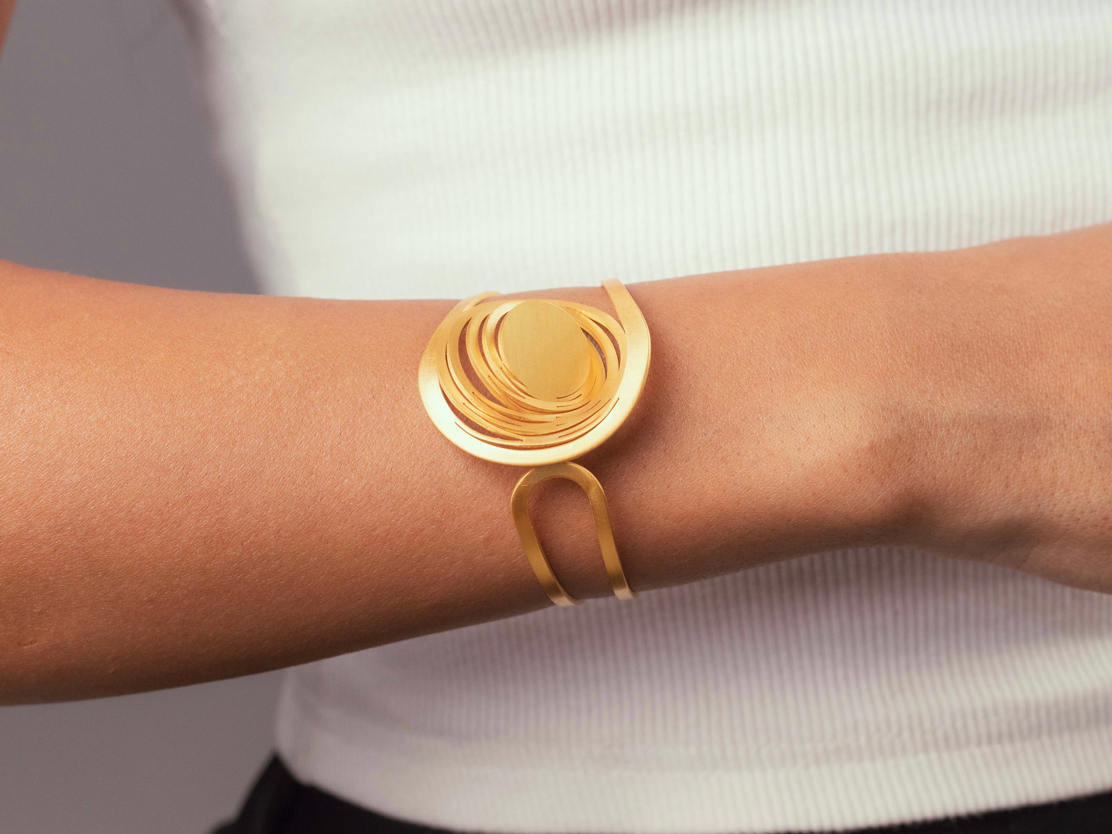 Gros plan sur la manchette Liquify Orbits dorée à l’or fin, bijou artisanal modulable au design contemporain signé Maison Niléa.