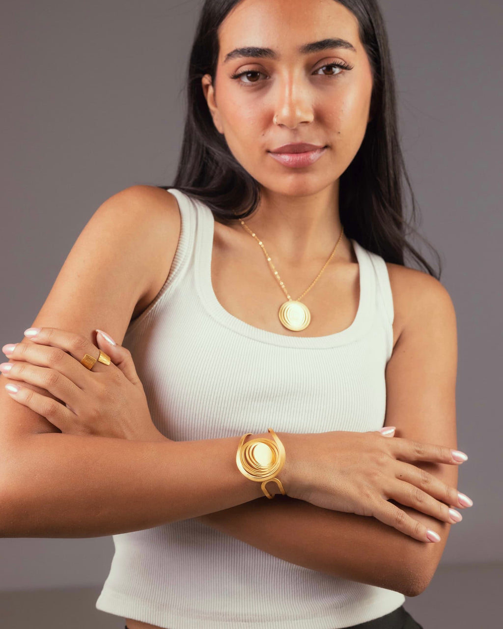 Femme portant la manchette Liquify Orbits, le collier assorti et la bague Liquify en laiton doré à l’or fin, bijoux artisanaux Maison Niléa