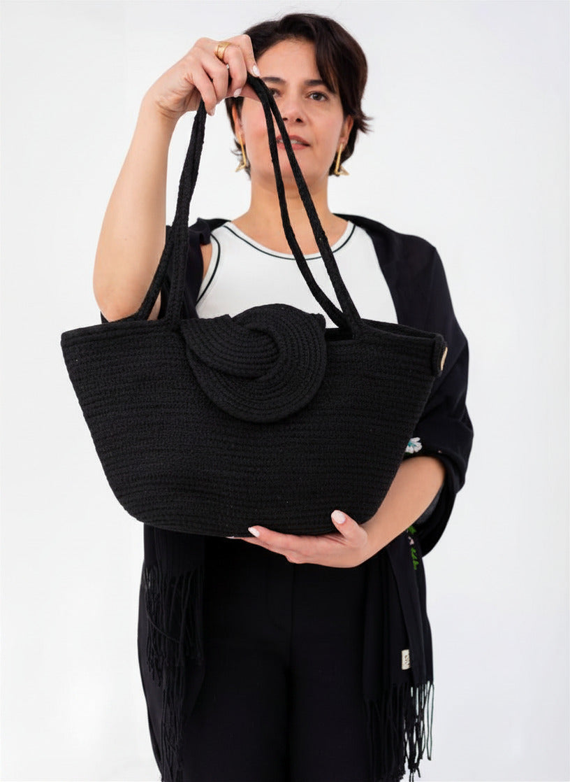 Vidéo de présentation du sac cabas Nout de Maison Niléa, montrant le sac noir pailleté en mouvement sous plusieurs angles pour révéler ses reflets scintillants, suivie d'une démonstration de l'ouverture de son rabat en spirale et de sa fermeture aimantée.
