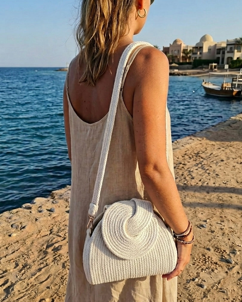 Sac bandoulière Gouna écru porté à l'épaule face à la mer - Maison Niléa
