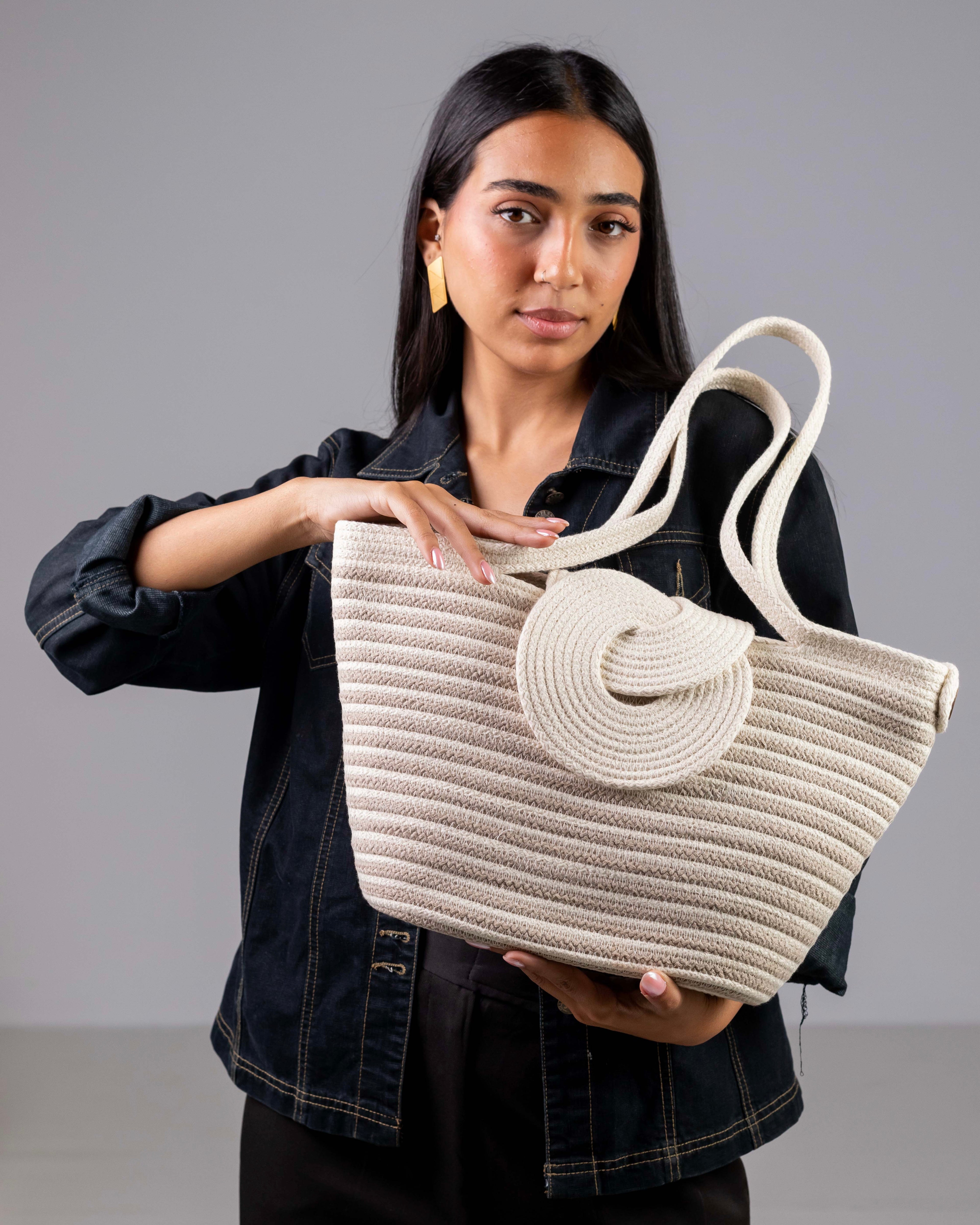 Une femme portant à l'épaule le grand sac cabas rayé Dahab de Maison Niléa, mettant en valeur sa taille idéale et son tombé élégant.