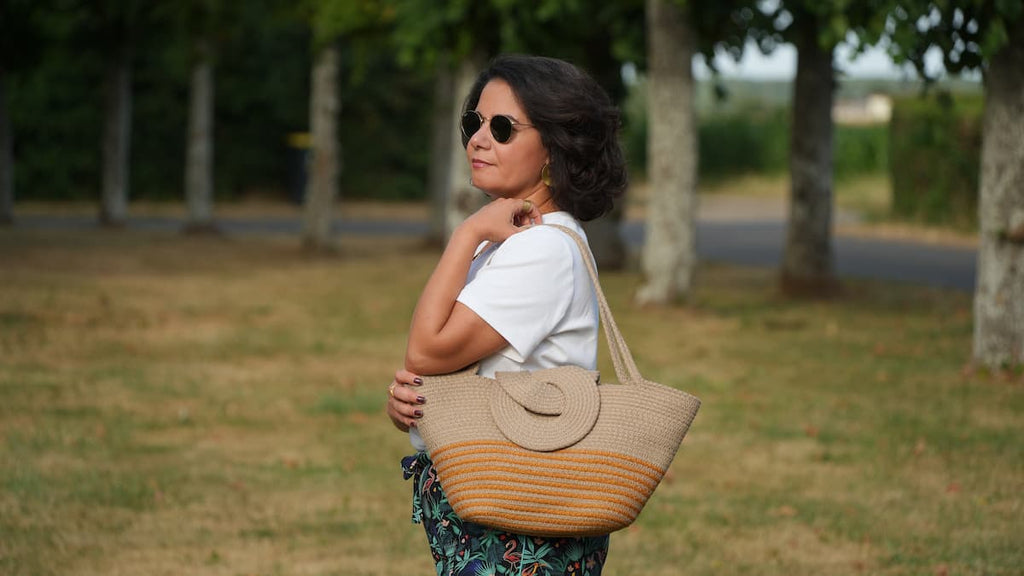 Le sac Louxor beige et orange Niléa est porté sur l'épaule dans un parc.