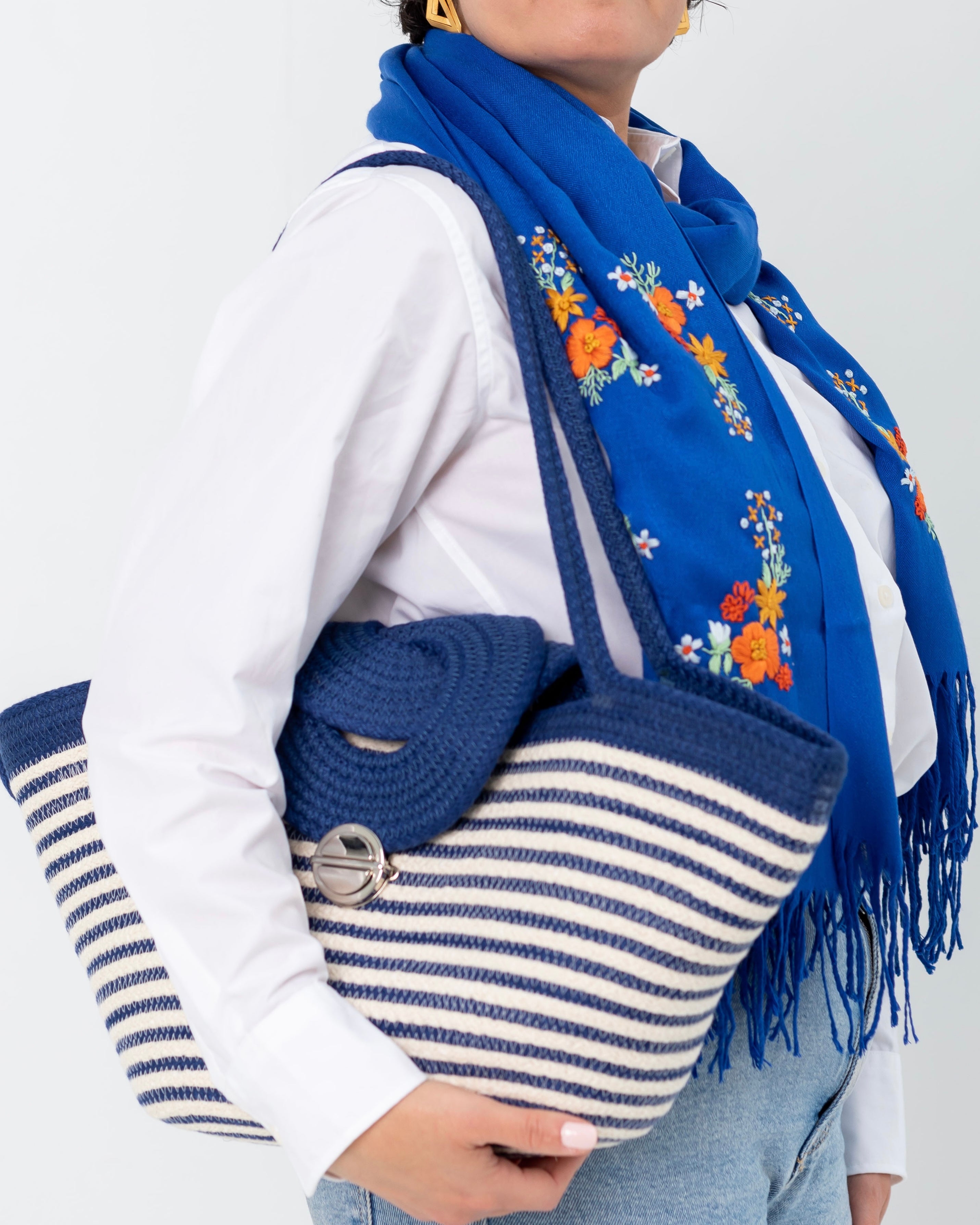 Sac à main marin Alexandrie porté à l’épaule avec l’écharpe Samar bleue.