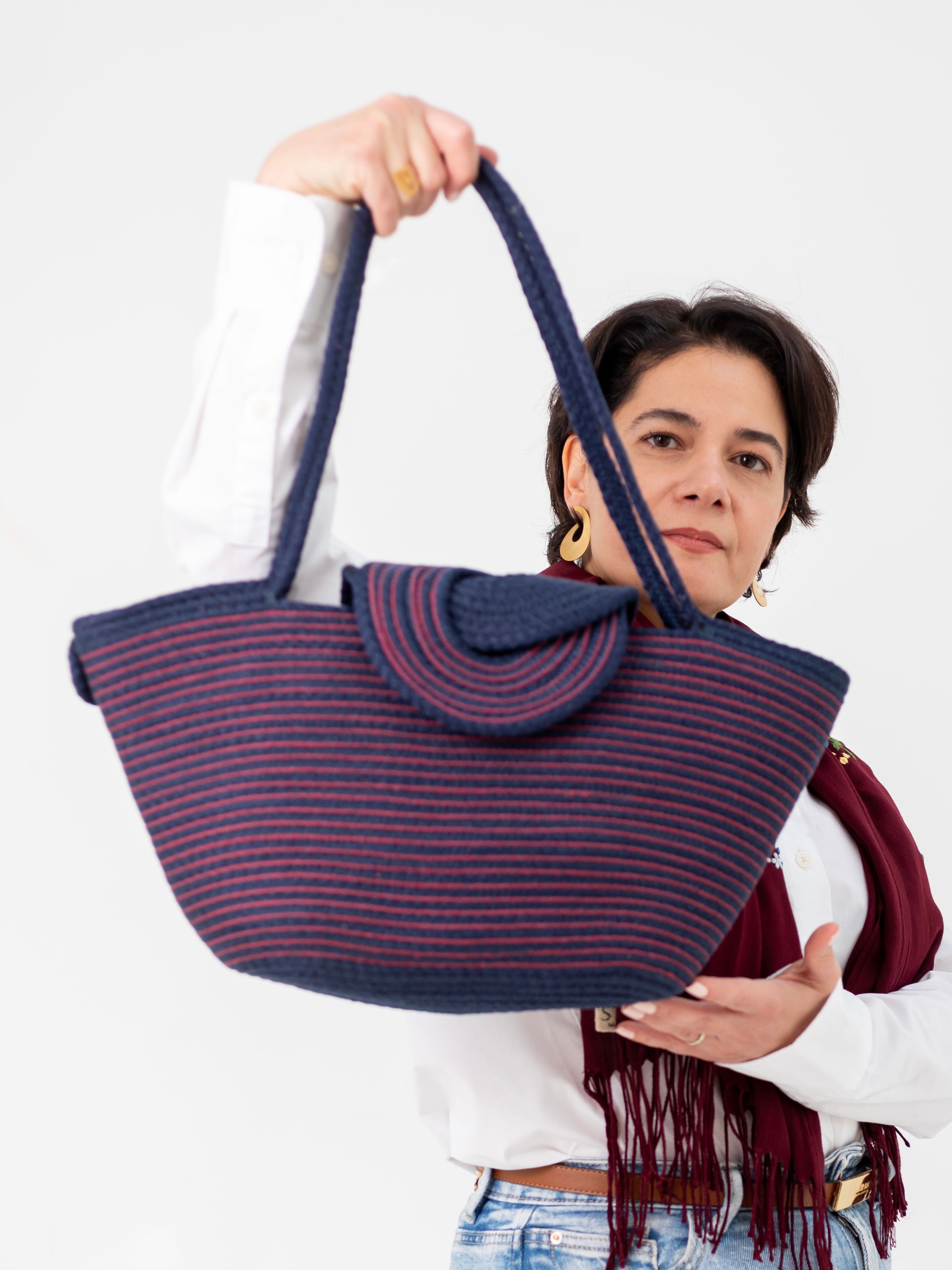 Le sac Marsa rayé bleu marine et rouge porté à la main.